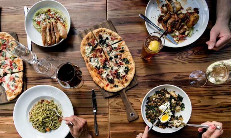 Wood table with plates full of pizza